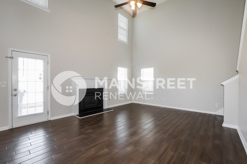 a renovated living room with hardwood floors and a door to the kitchen