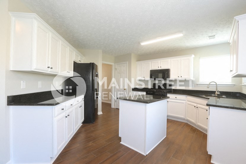 a renovated kitchen with white cabinets and black counter tops