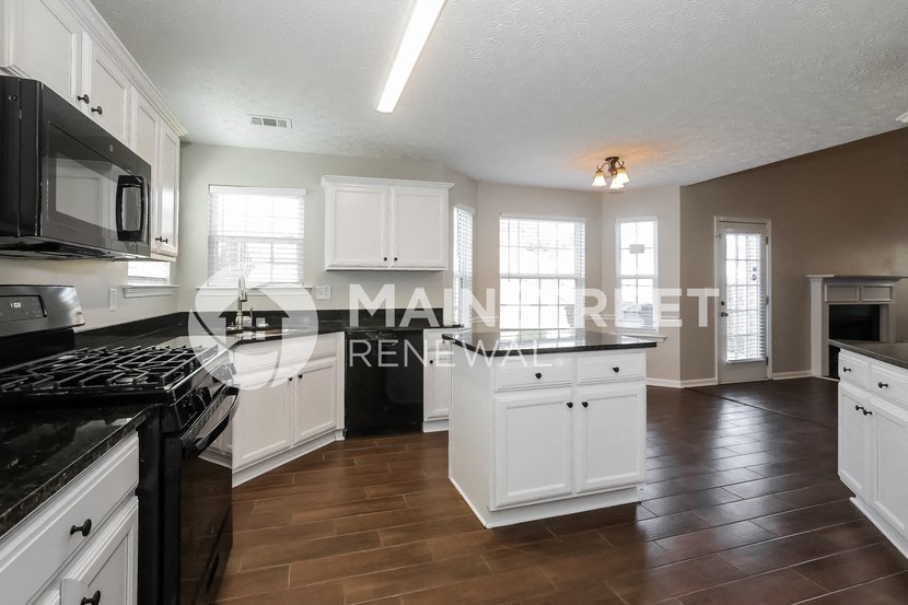 a renovated kitchen with white cabinets and black counter tops