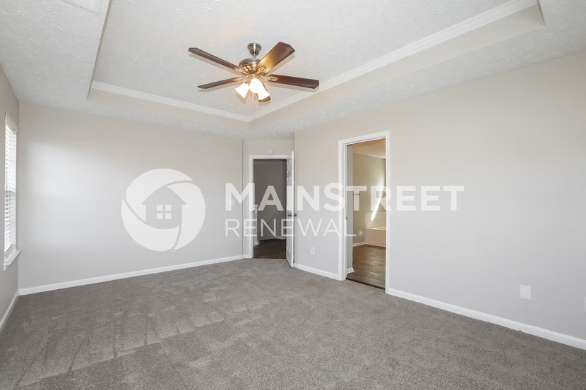 a living room with carpet and a ceiling fan