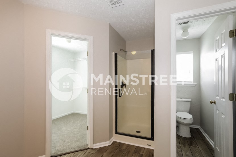 a white bathroom with a walk in shower and a toilet