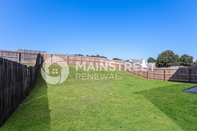 a backyard with a wooden fence and grass