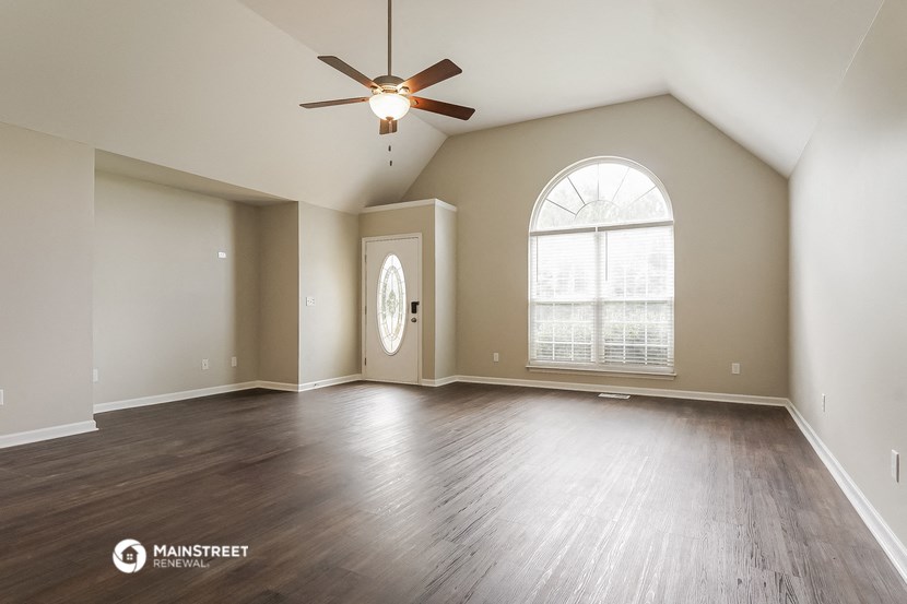 an empty living room with a ceiling fan and a large window
