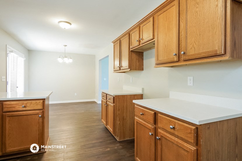 a kitchen with wooden cabinets and white counter tops and a large window