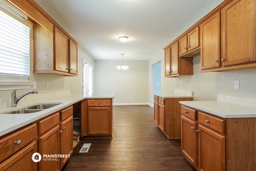 a kitchen with wooden cabinets and white counter tops and a sink