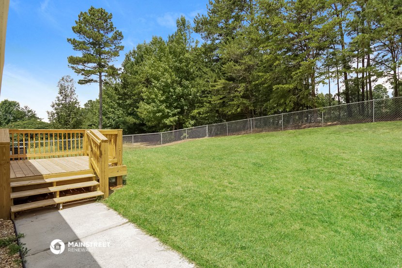 a backyard with a wooden deck and a chain link fence