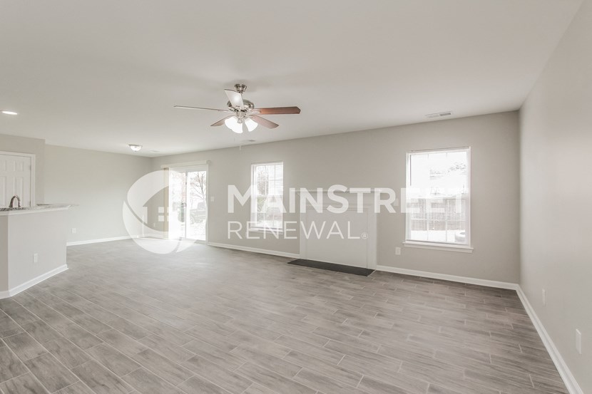 a white and gray living room with a ceiling fan
