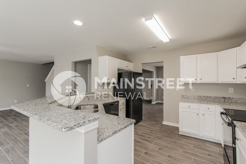 a renovated kitchen with granite counter tops and white cabinets