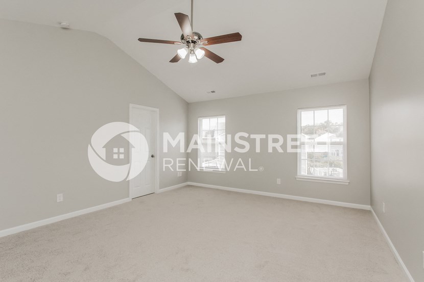a bedroom with a large empty room with a ceiling fan