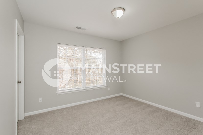 a bedroom with a carpeted floor and a large window