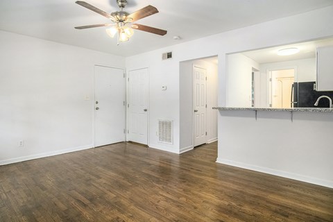 an empty living room with white walls and a ceiling fan