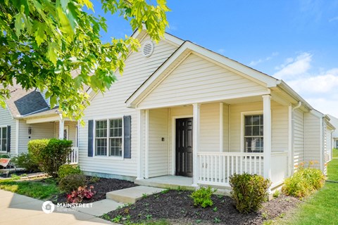 a white house with a front porch and a tree