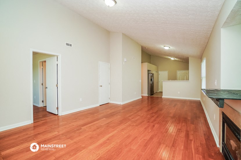 a spacious living room with wood flooring and white walls
