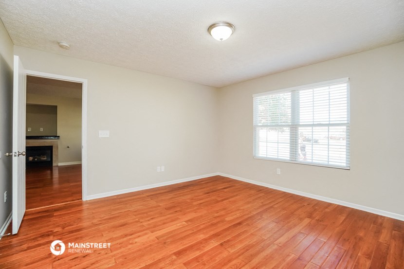 the spacious living room with wood flooring and a large window