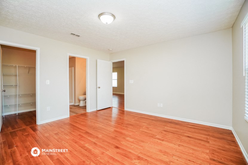 an empty living room with wood flooring and a bathroom