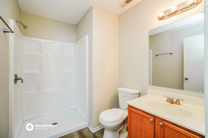 a bathroom with a shower toilet and sink and a mirror