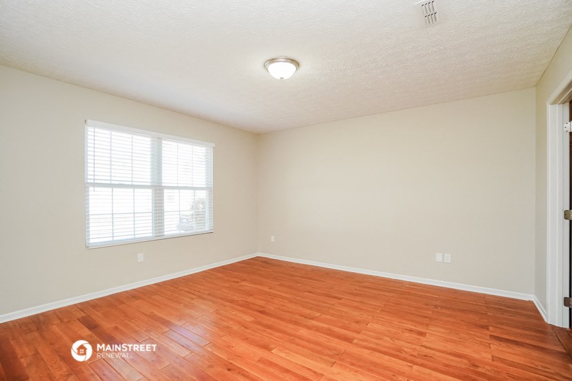the spacious living room with hardwood flooring and a window