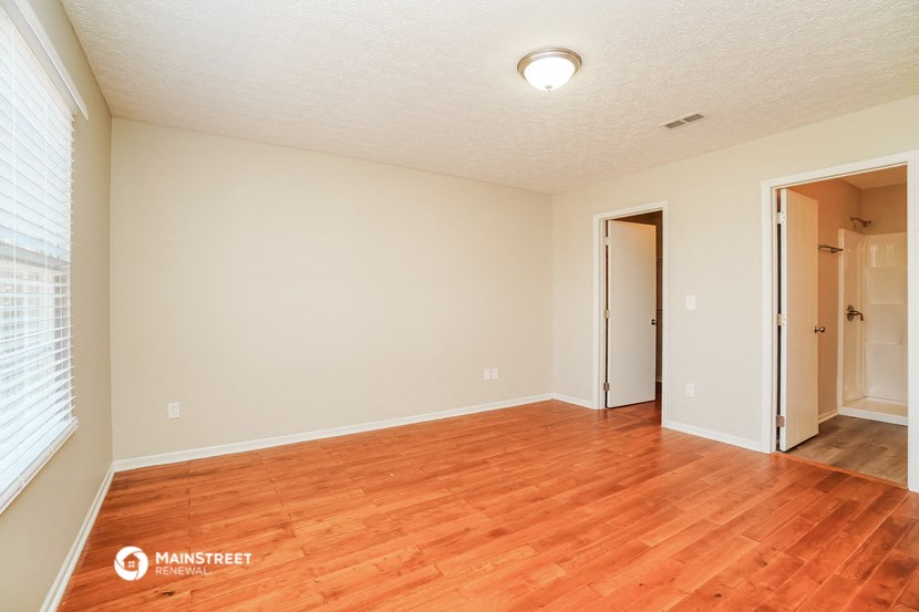 the spacious living room with hardwood flooring and white walls