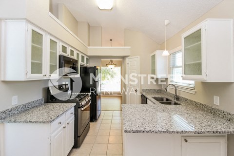 a renovated kitchen with granite counter tops and white cabinets