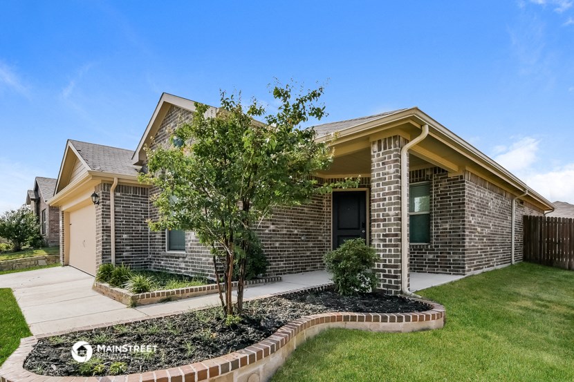 a brick house with a yard and a tree in front of it