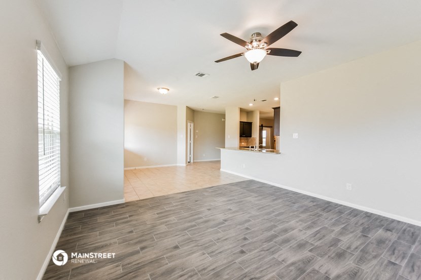 an empty living room with a ceiling fan
