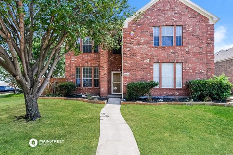 a brick house with a sidewalk in front of it