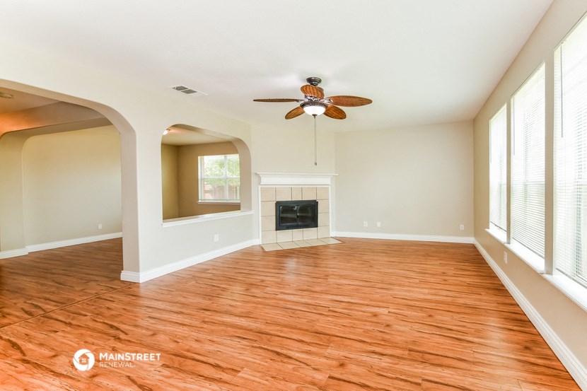 the living room with wood flooring and a ceiling fan