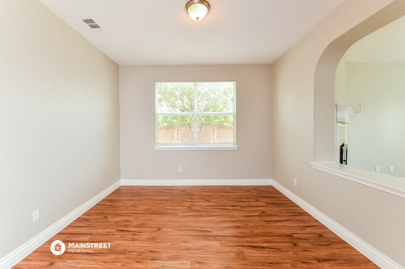 the spacious living room with hardwood flooring and a window