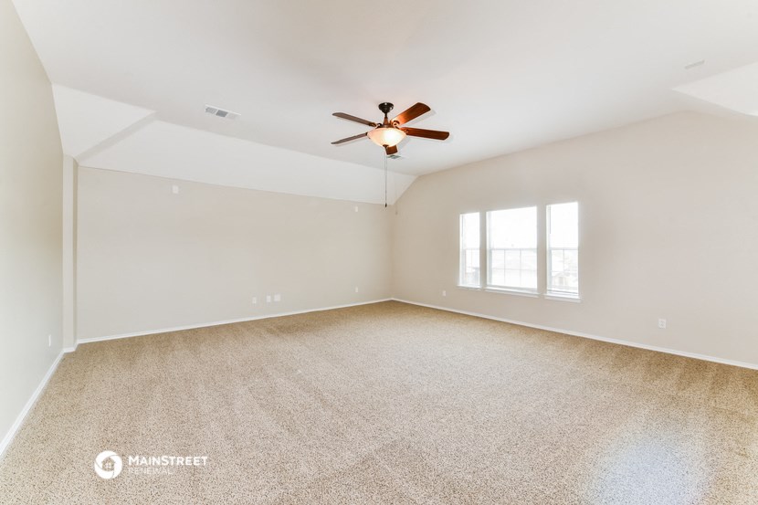 an empty living room with a ceiling fan and a window