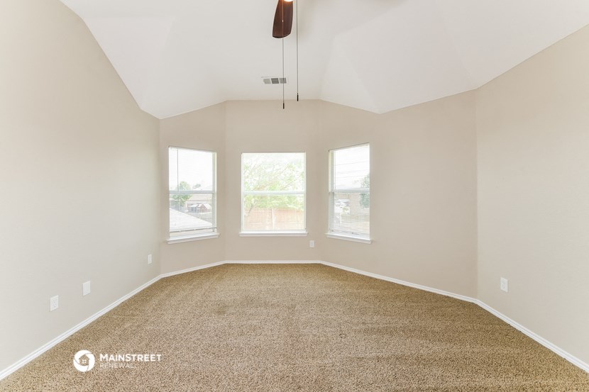the living room of a home with carpet and three windows