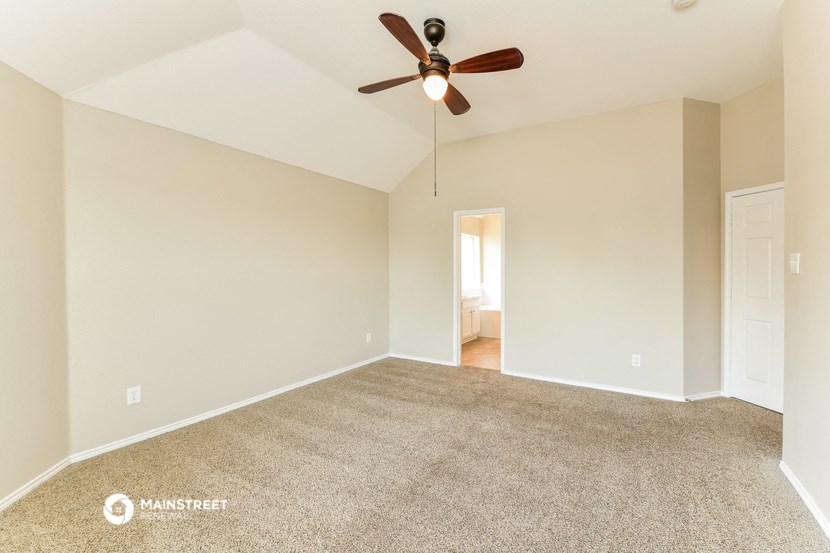 the spacious living room with ceiling fan and carpet