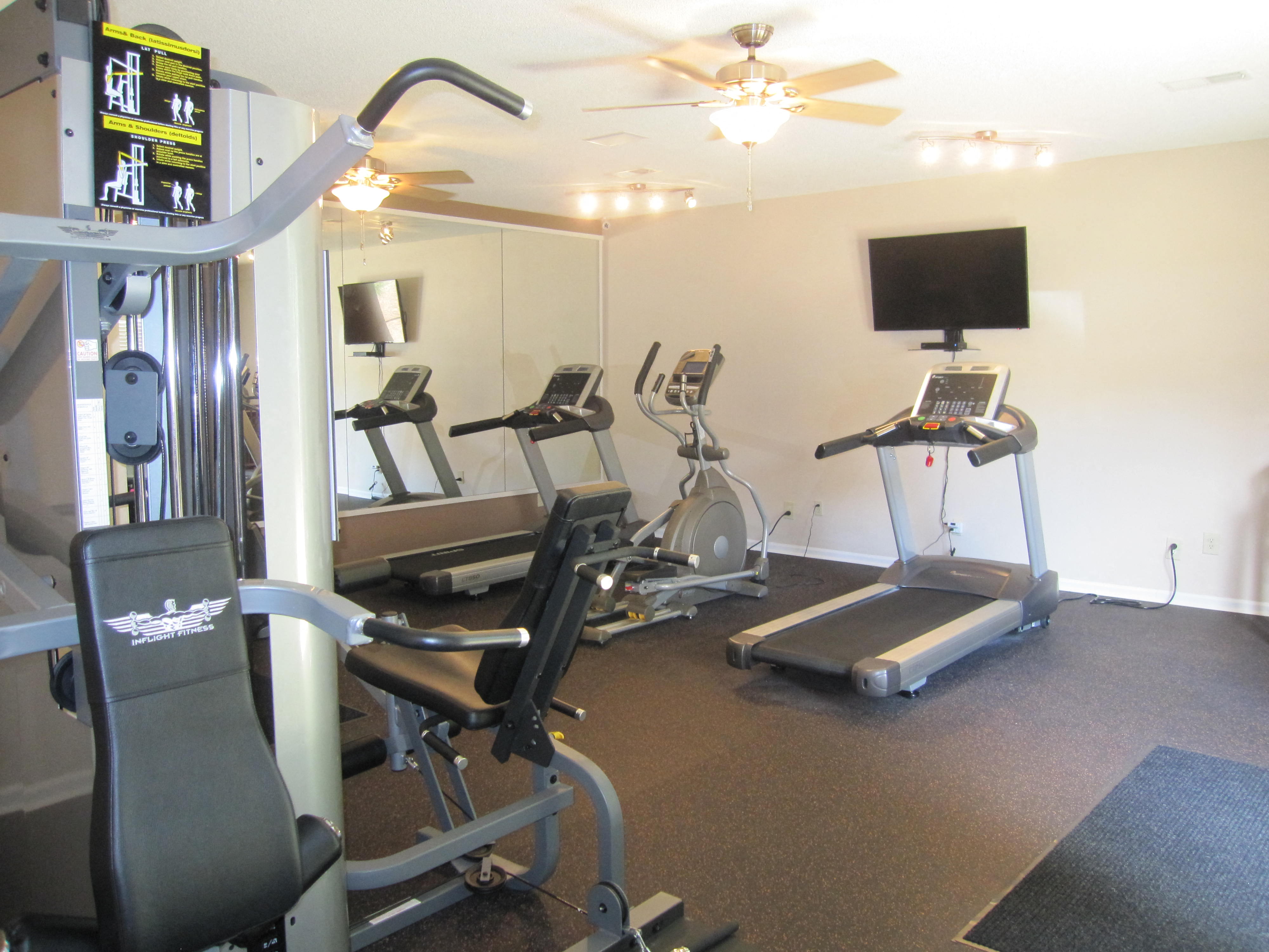 a gym with various exercise equipment and a tv