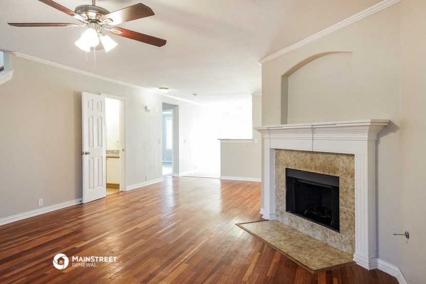 an empty living room with a fireplace and a ceiling fan