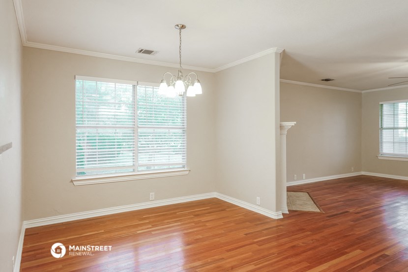 an empty living room with wood floors and a large window