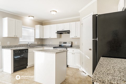 a kitchen with white cabinets and a black refrigerator