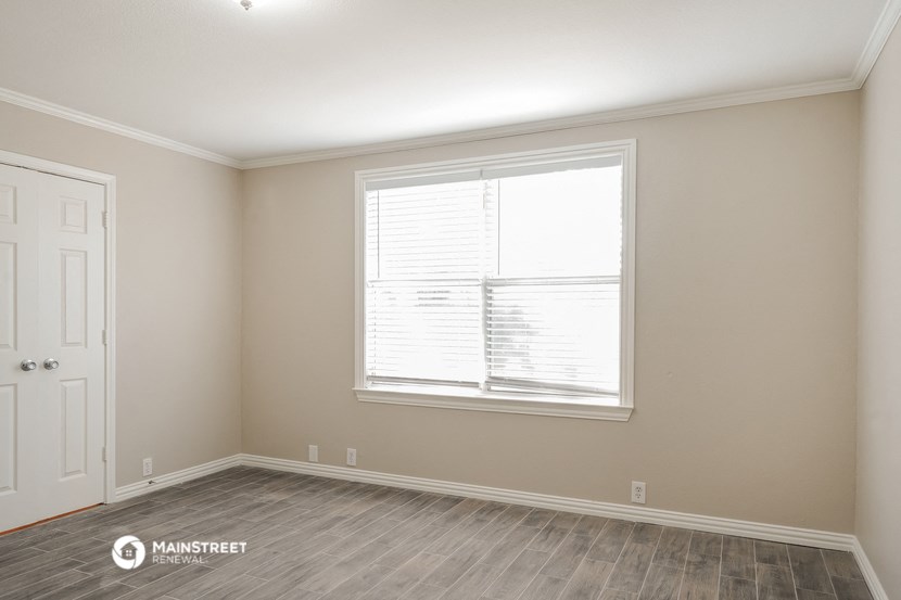 the spacious living room with a large window and wood flooring