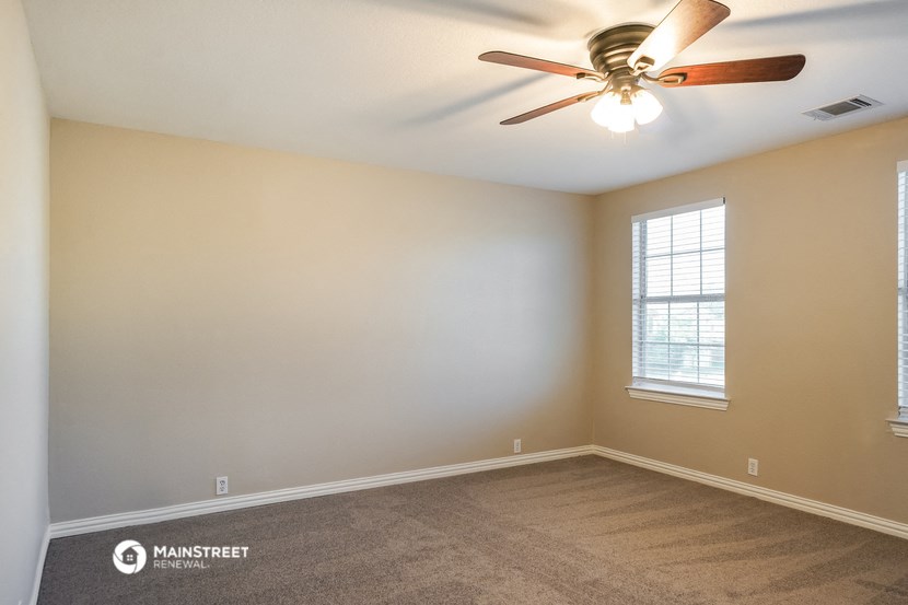 an empty living room with a ceiling fan and a window