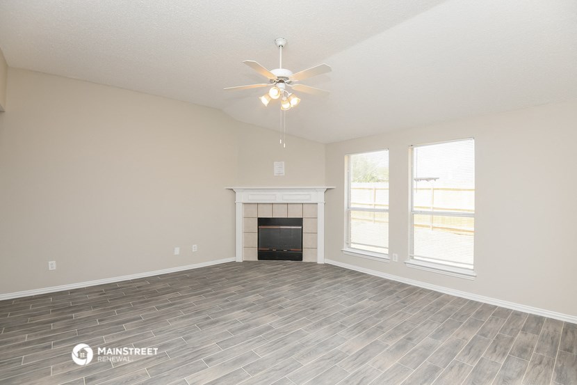 the living room with a fireplace and a ceiling fan