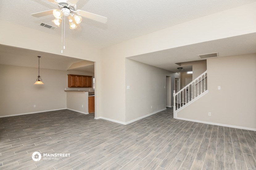 the living room and kitchen of an empty house with a ceiling fan