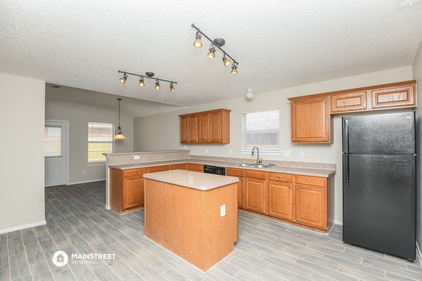 a kitchen with wooden cabinets and a black refrigerator