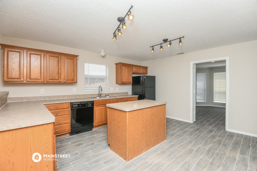 a kitchen with wooden cabinets and a black refrigerator
