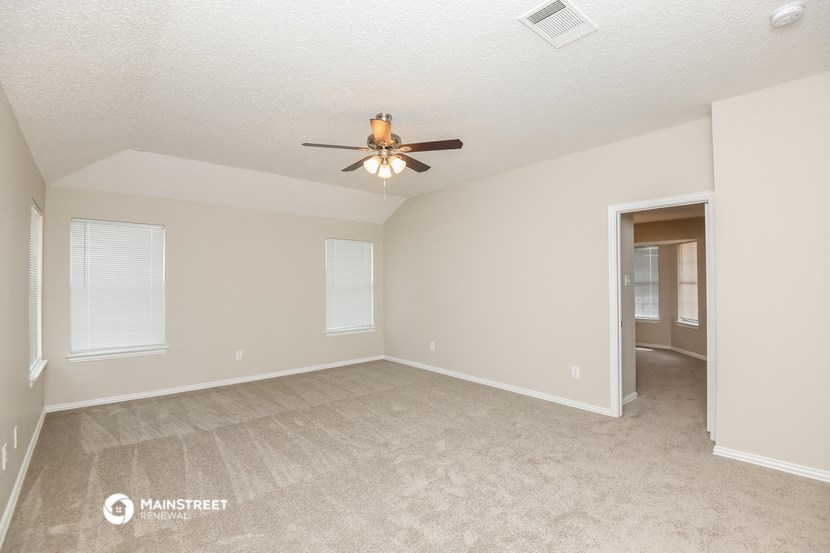 the spacious living room with ceiling fan and carpeting