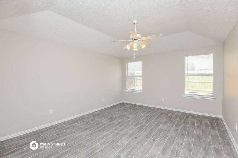 the spacious living room with vinyl flooring and a ceiling fan