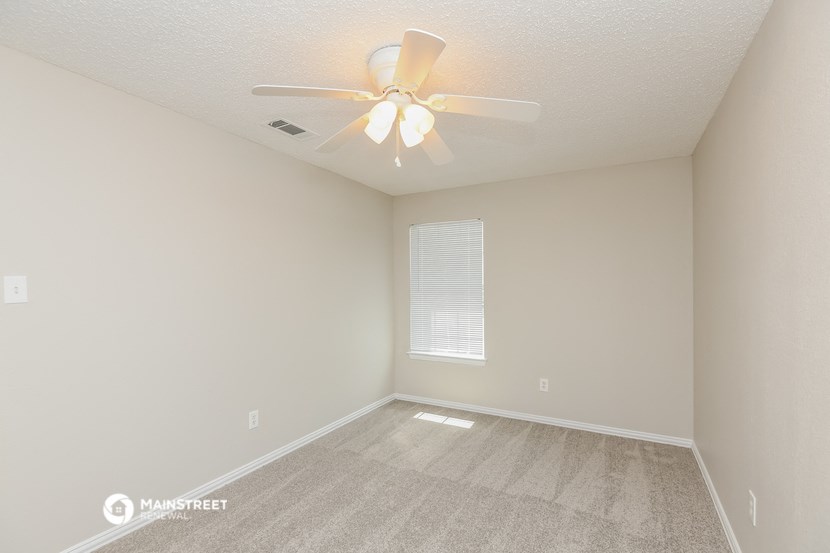the spacious living room with ceiling fan and carpet