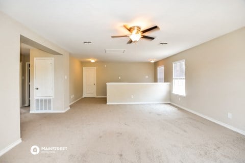 the spacious living room and dining room with ceiling fan and white carpet