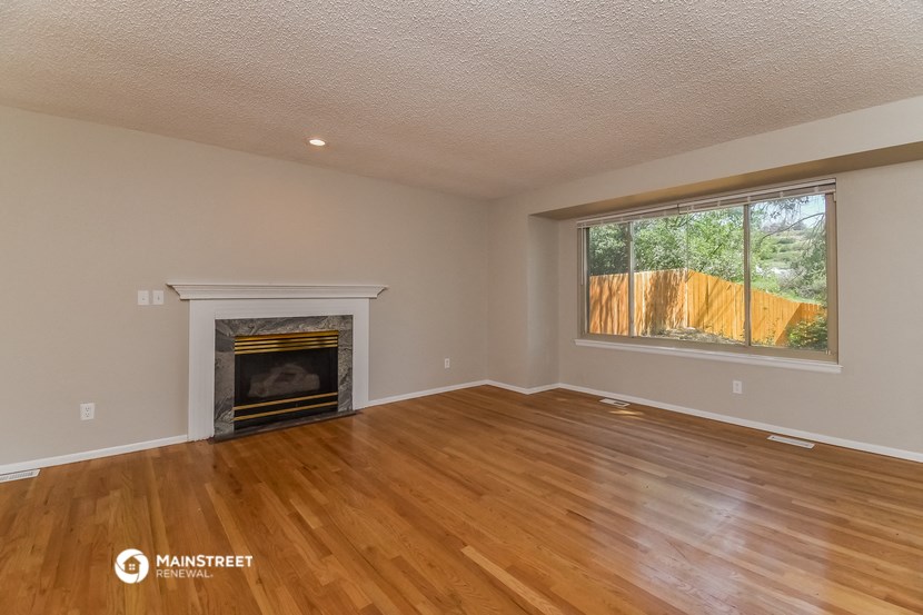 the living room with wood floors and a fireplace