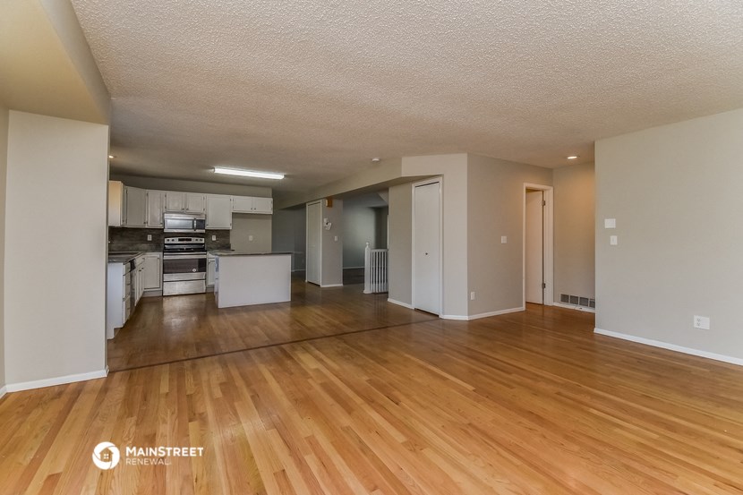 the living room and kitchen of an apartment with wood flooring