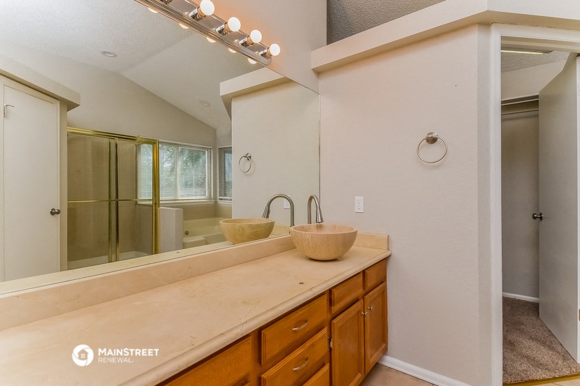 the master bathroom has a large vanity with two sinks and a large mirror