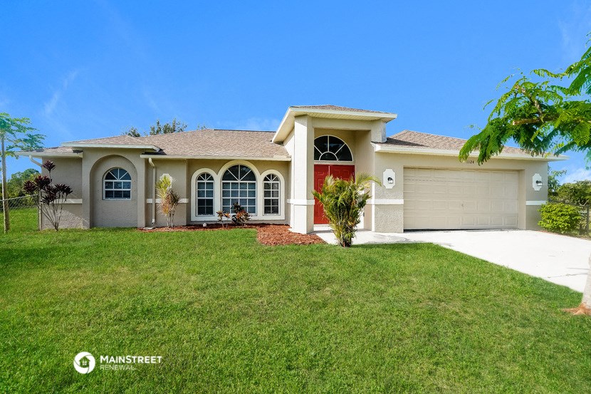 a beige house with a garage and a lawn