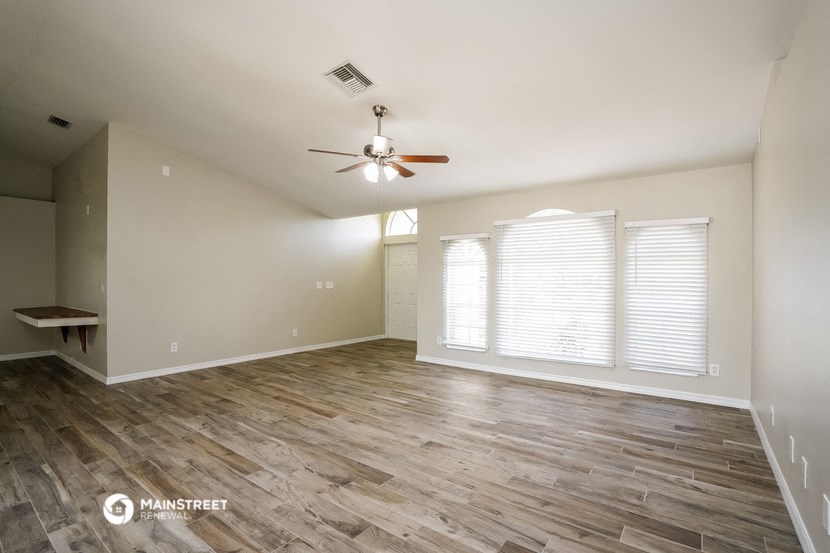 the living room with wood flooring and a ceiling fan